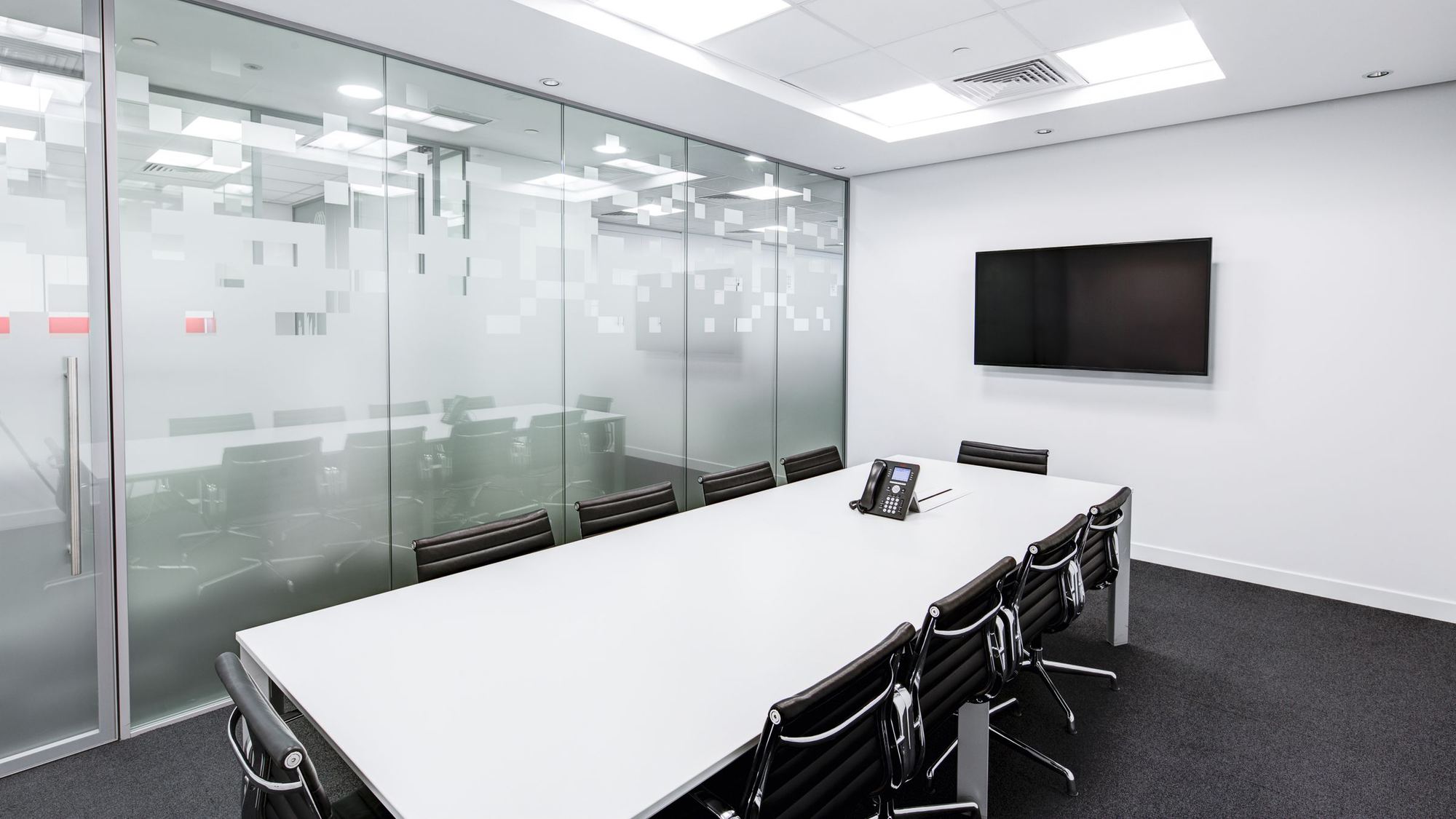 Empty conference room with a long table and a wall screen