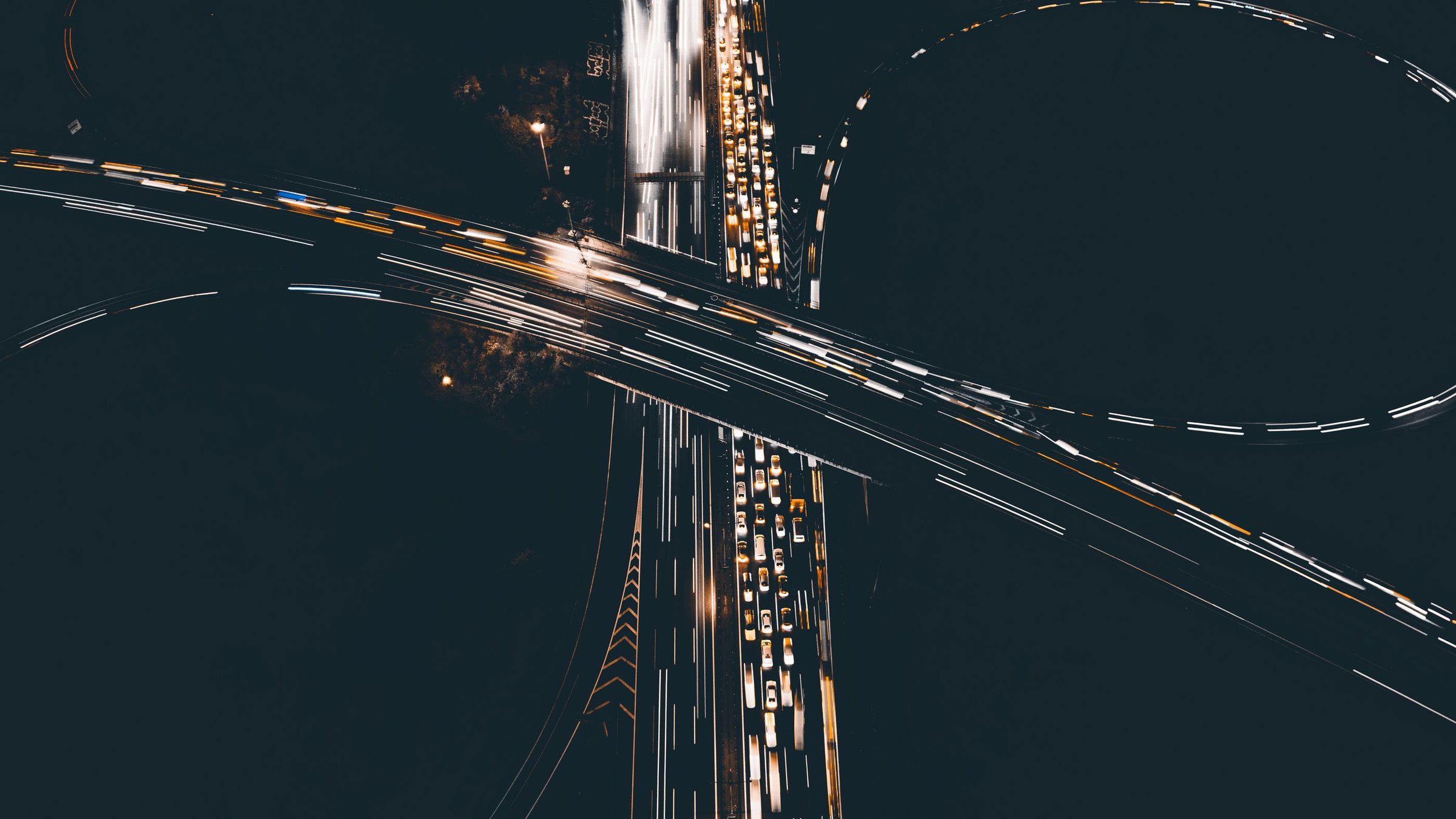 Highway interchange at night seen from above, with light trails in every lane