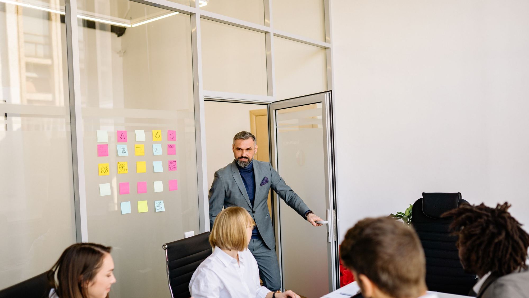 Manager leading a meeting in a glass-walled office