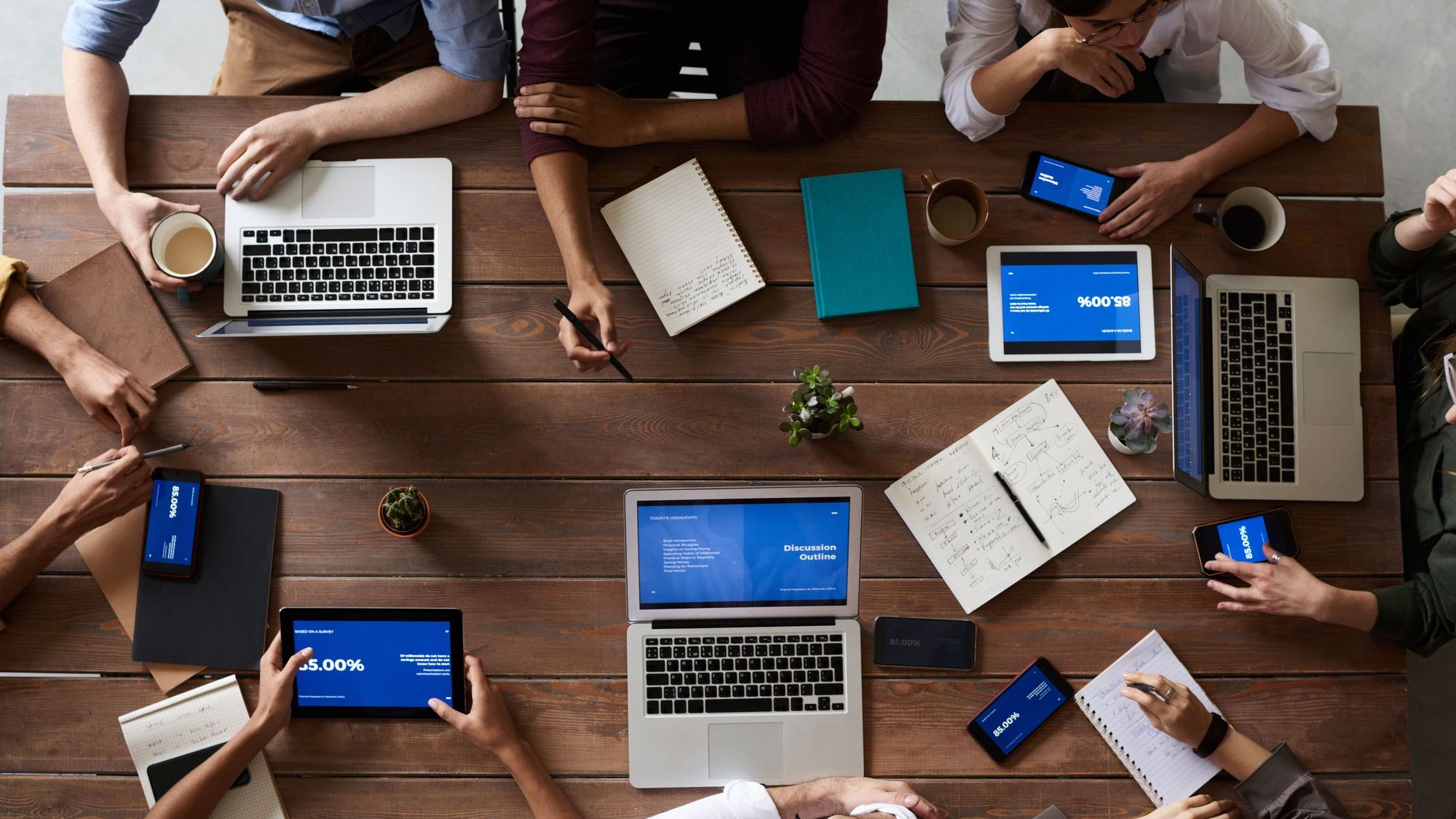 Overhead view of a team working with laptops and notebooks at a table