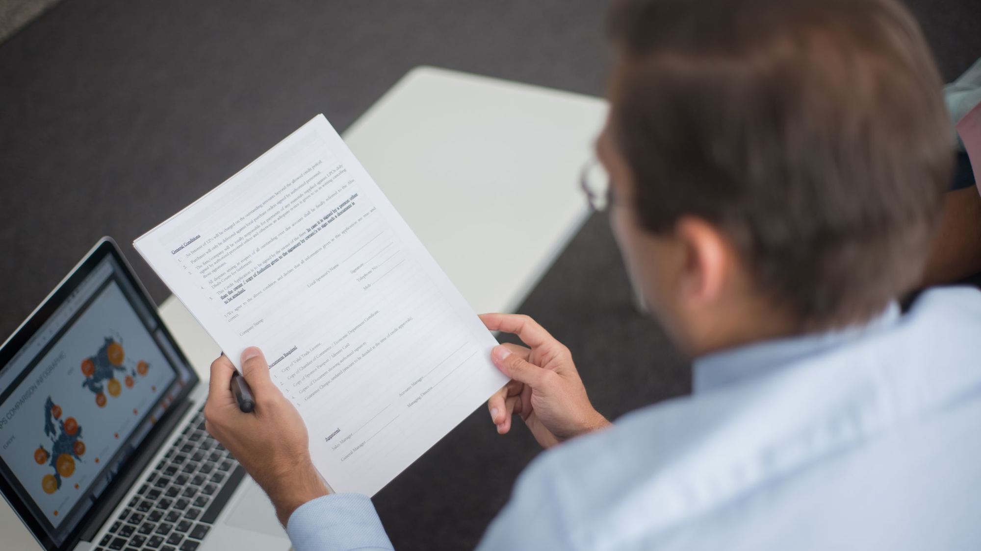 Person reviewing a printed report next to a tablet
