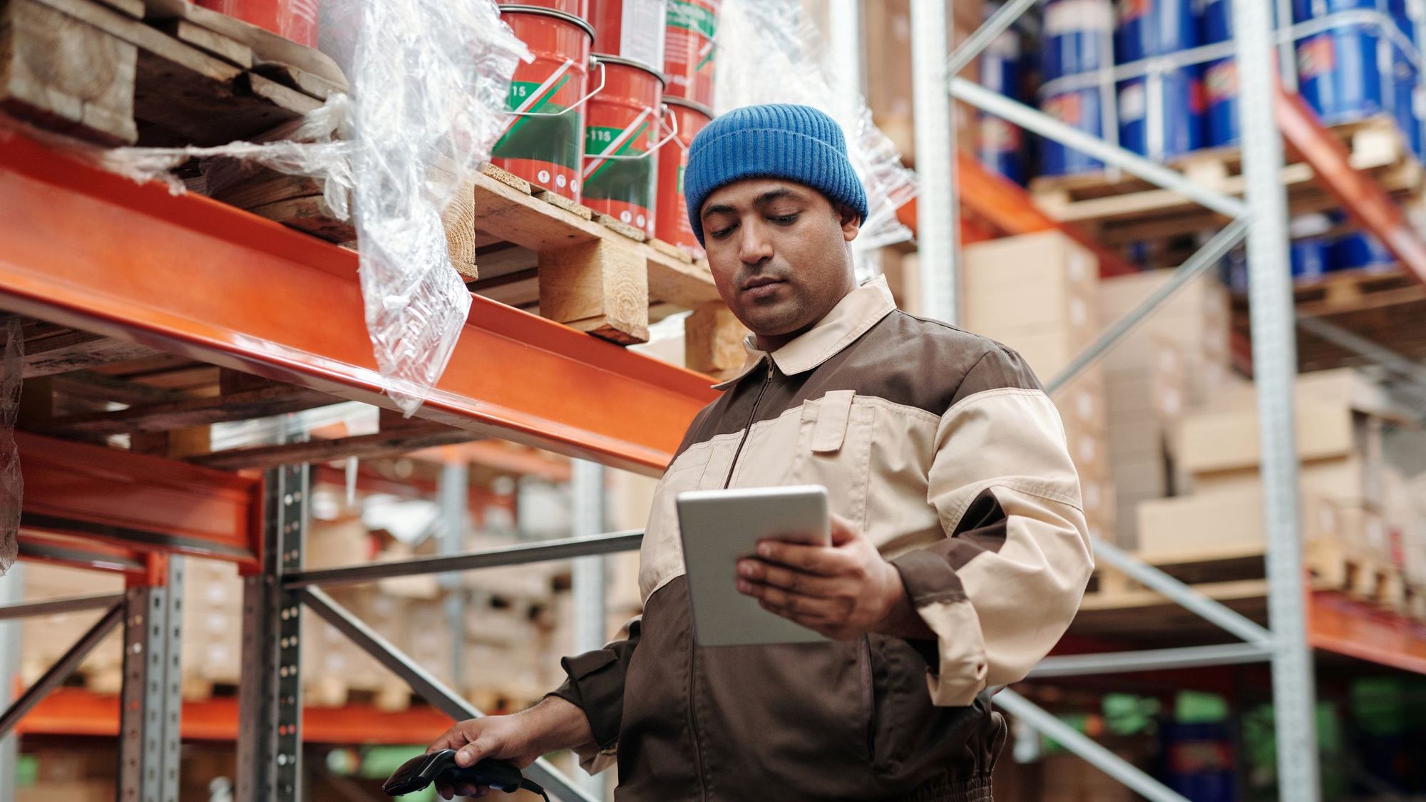 Warehouse worker checking a tablet beside storage racks
